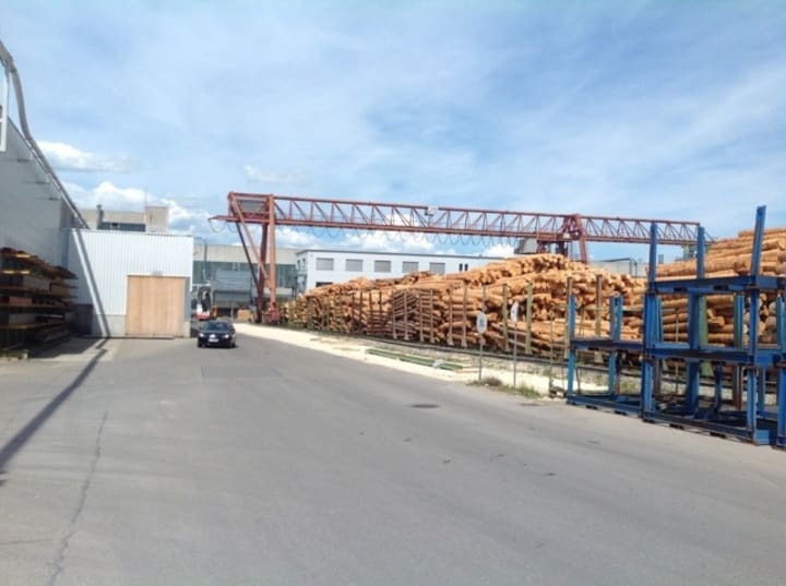 a lot of wood stacked up with a car driving along