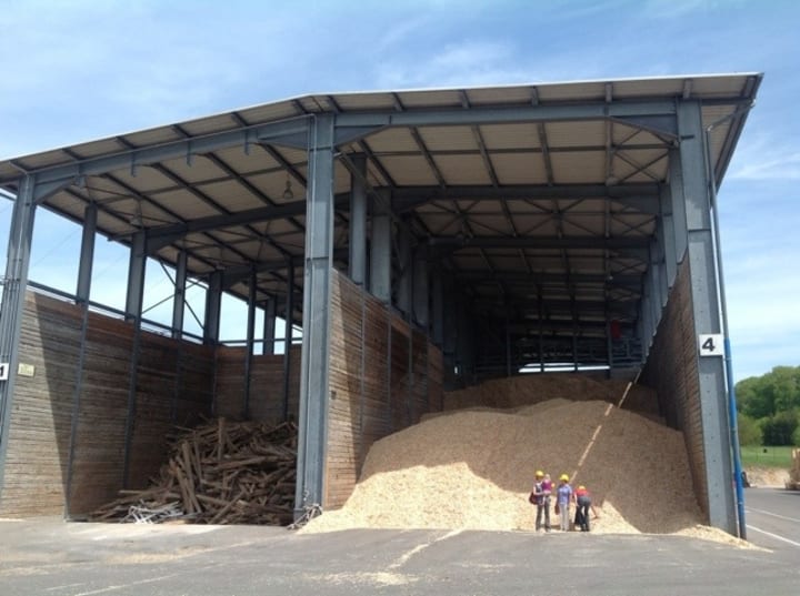 massive pile of wood chippings with people stood in front to give a sense of scale