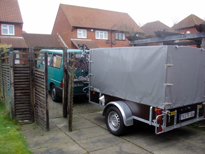 A Green VW Transporter Bus with a grey trailer attached behind.