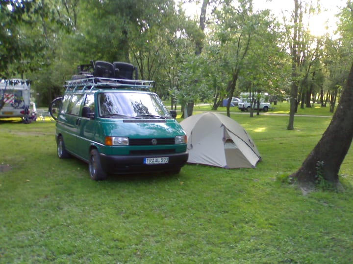 Pitched tent next to very full VW Bus.