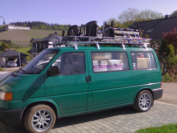 Green VW Transporter Bus with roof rack and completely full inside.