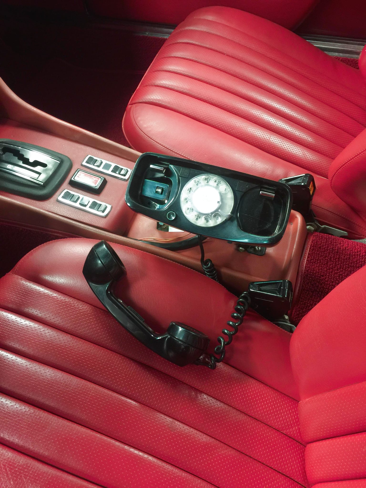 Old school black car phone in red leather interior