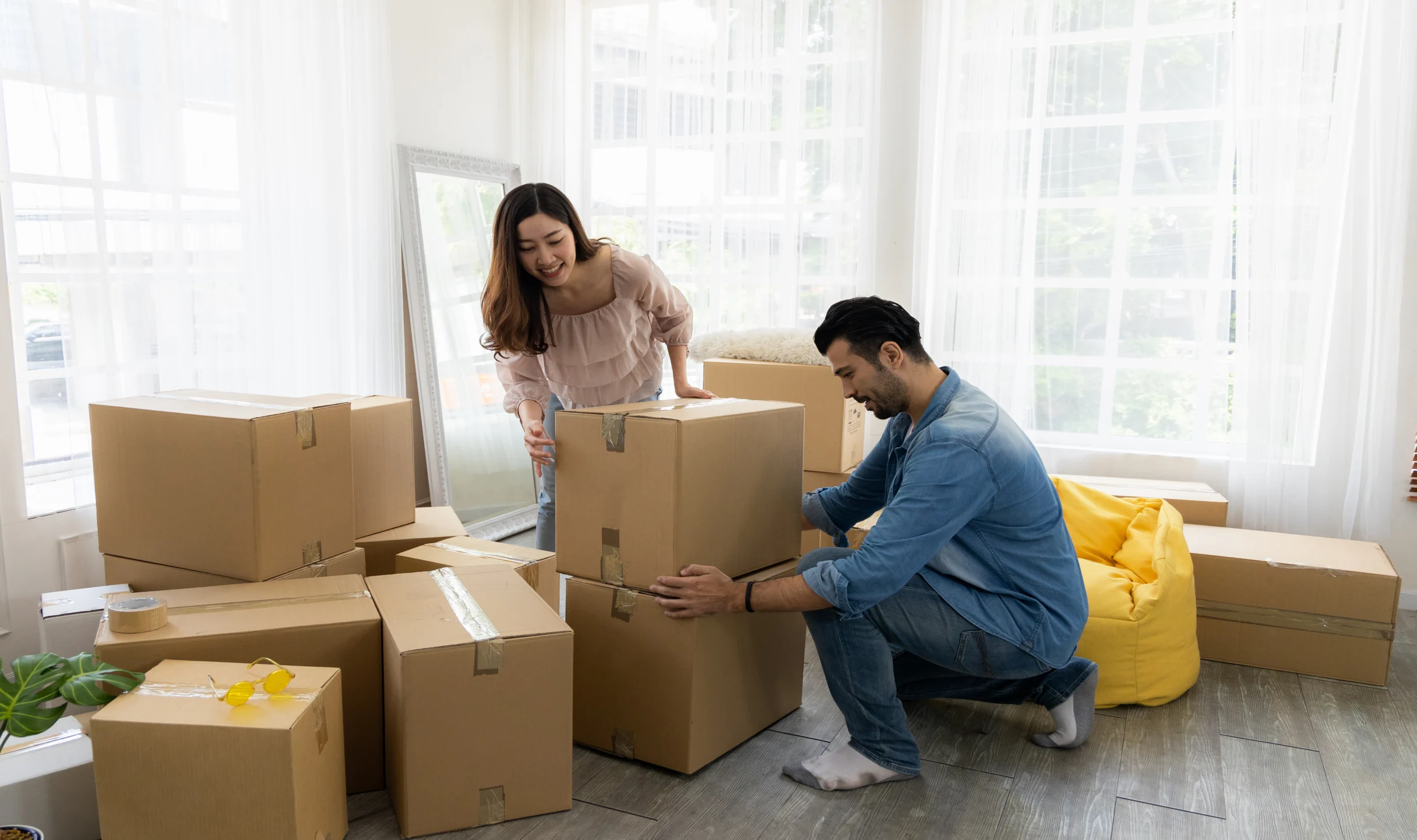 A happy couple in a bright room moving in Fort Worth and packing boxes