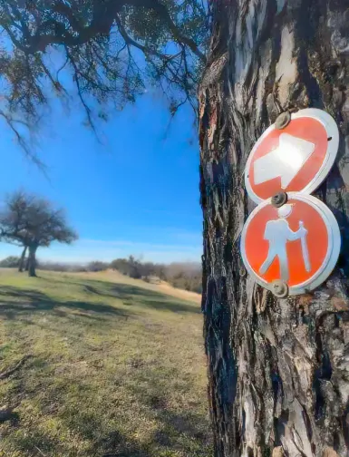 Hiking signs posted on tree at John Griggs Park in Aledo, Texas