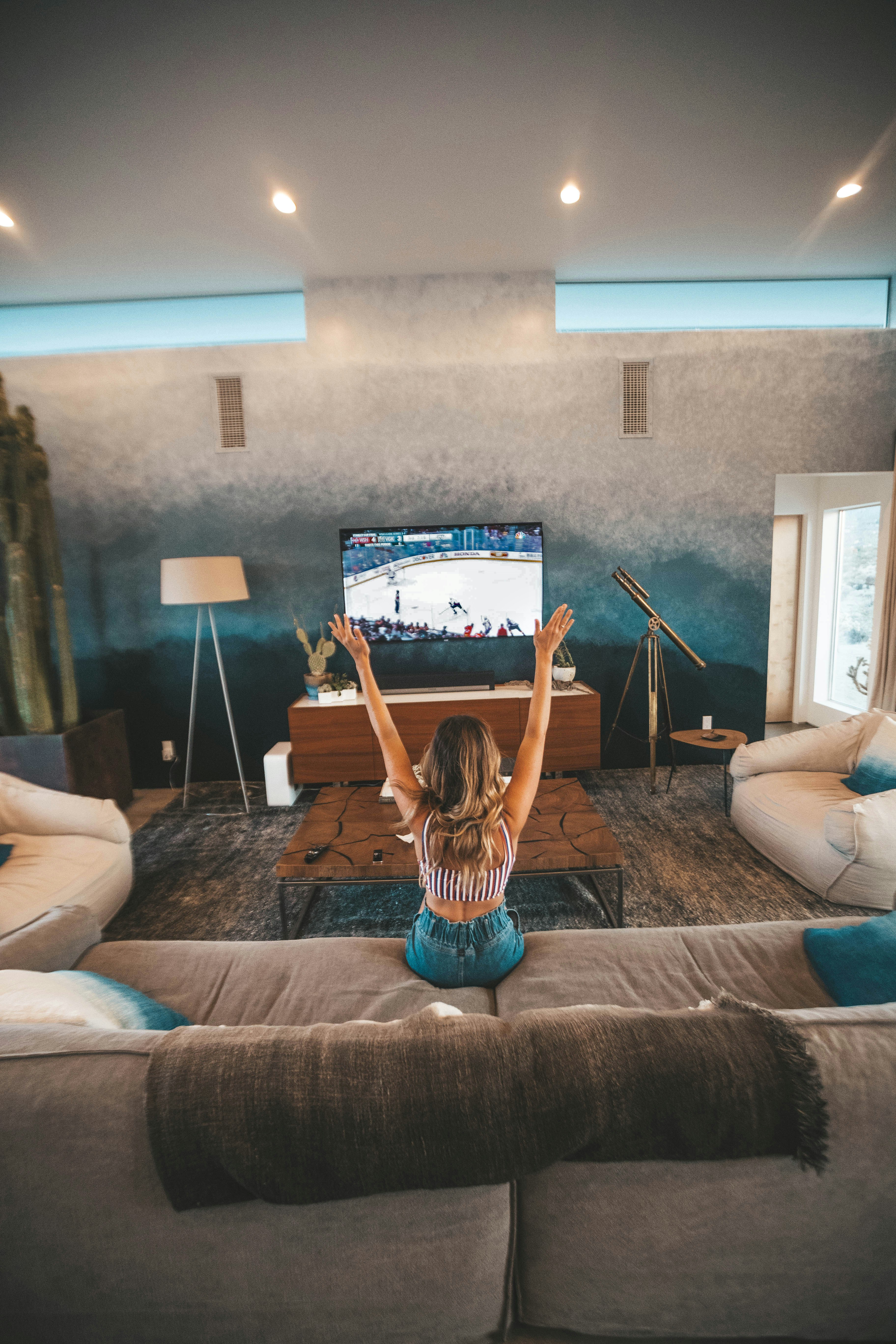 Woman cheering on her favorite hockey team on a large flat screen TV in her living room