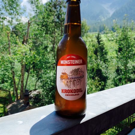 une biere rousse du nom de Krokodil de la brasserie Monsteiner de Davos. Sur l'étiquette figure une locomotive Crocodile. En arrière plan, les montagnes du Parc Ela aux Grisons