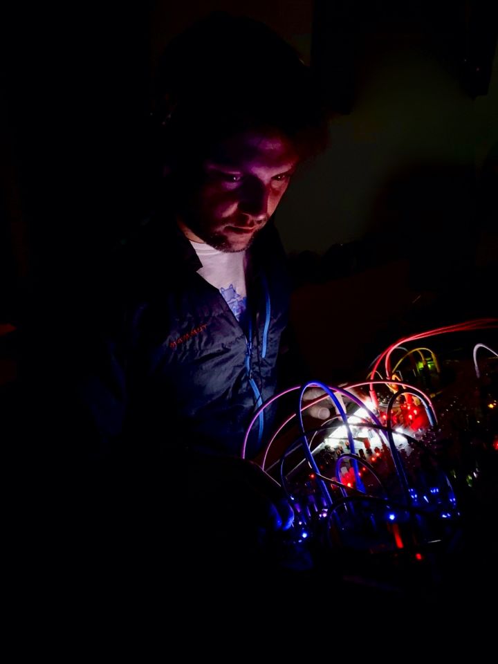 Photo of me in the dark. My face is lit by the leds of my eurorack system.