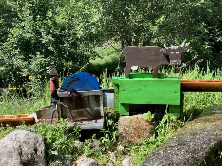 Une petie vache en bois fabriquée de manière artisanale mange du fourage. Elle est actionné par une petite roue à aube.