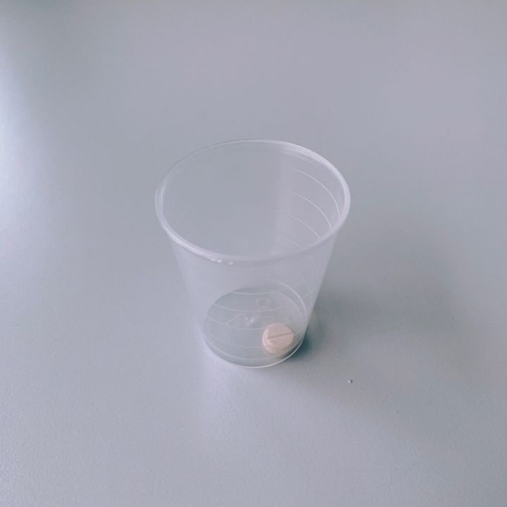 Une pilule dans un verre en plastique transparent