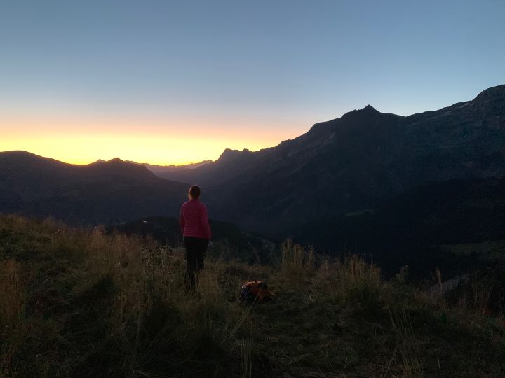 Le soleil se lève derrière les montagne. Au premier plan Céline dans la peine ombre le regarde