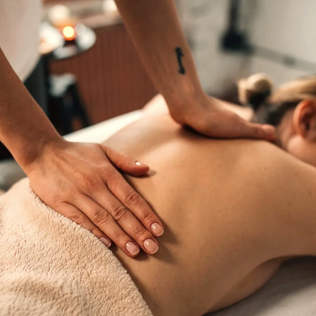 A full-body relaxing massage in progress in a warm, dim studio.