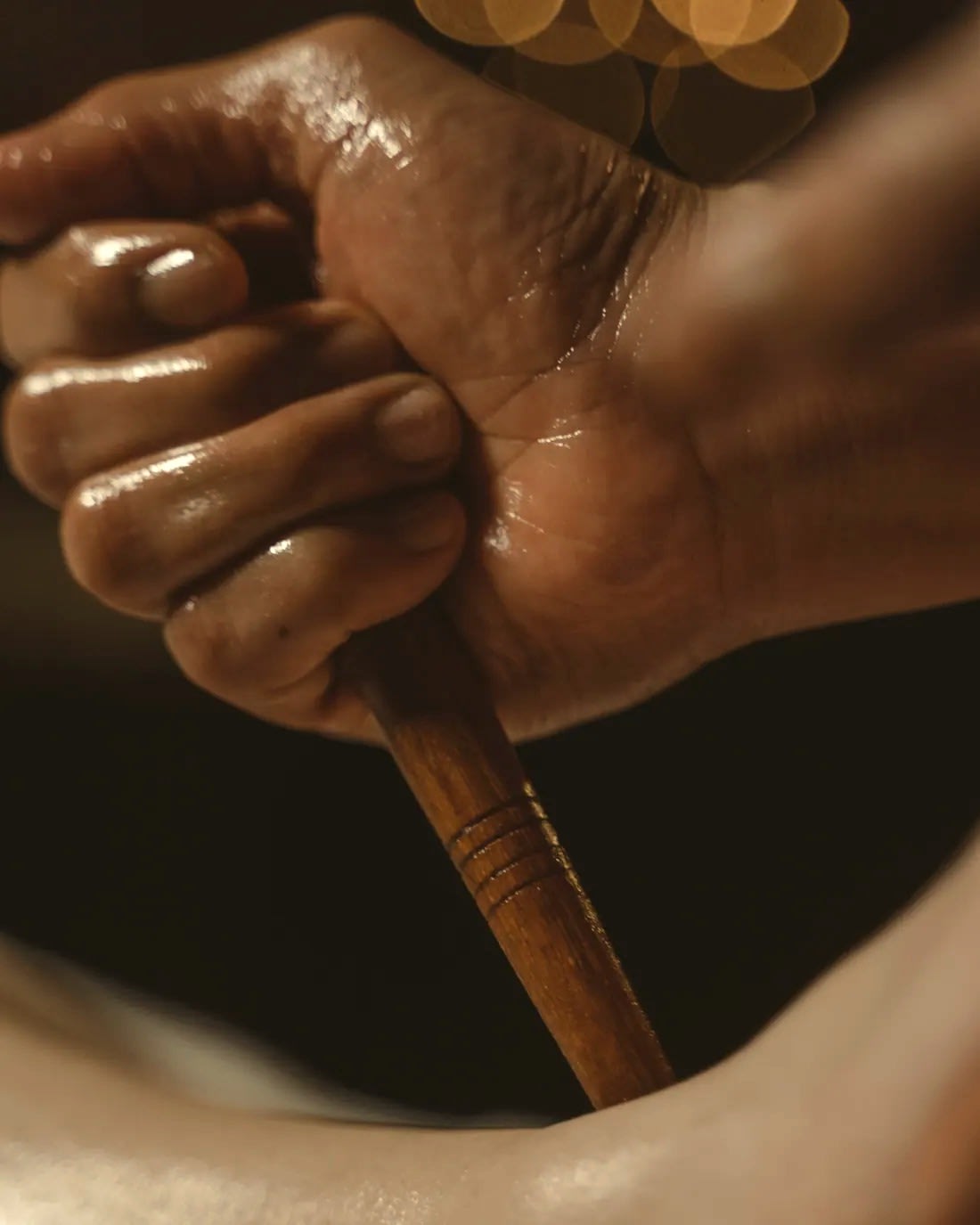 A wooden maderoterapia tool worked over the skin by hand.