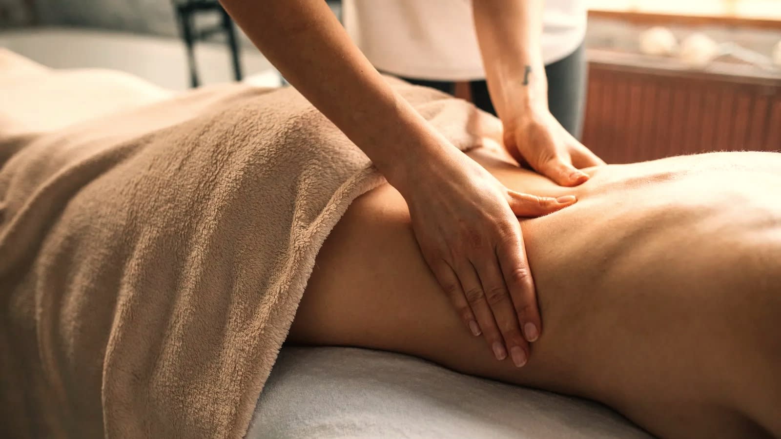 Hands working the thigh and hip by hand during a body contouring session.