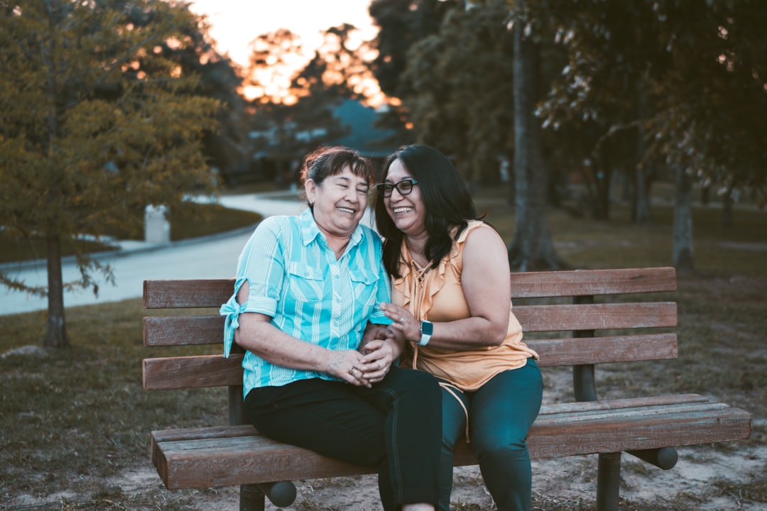 2 women smiling on a bench outside
