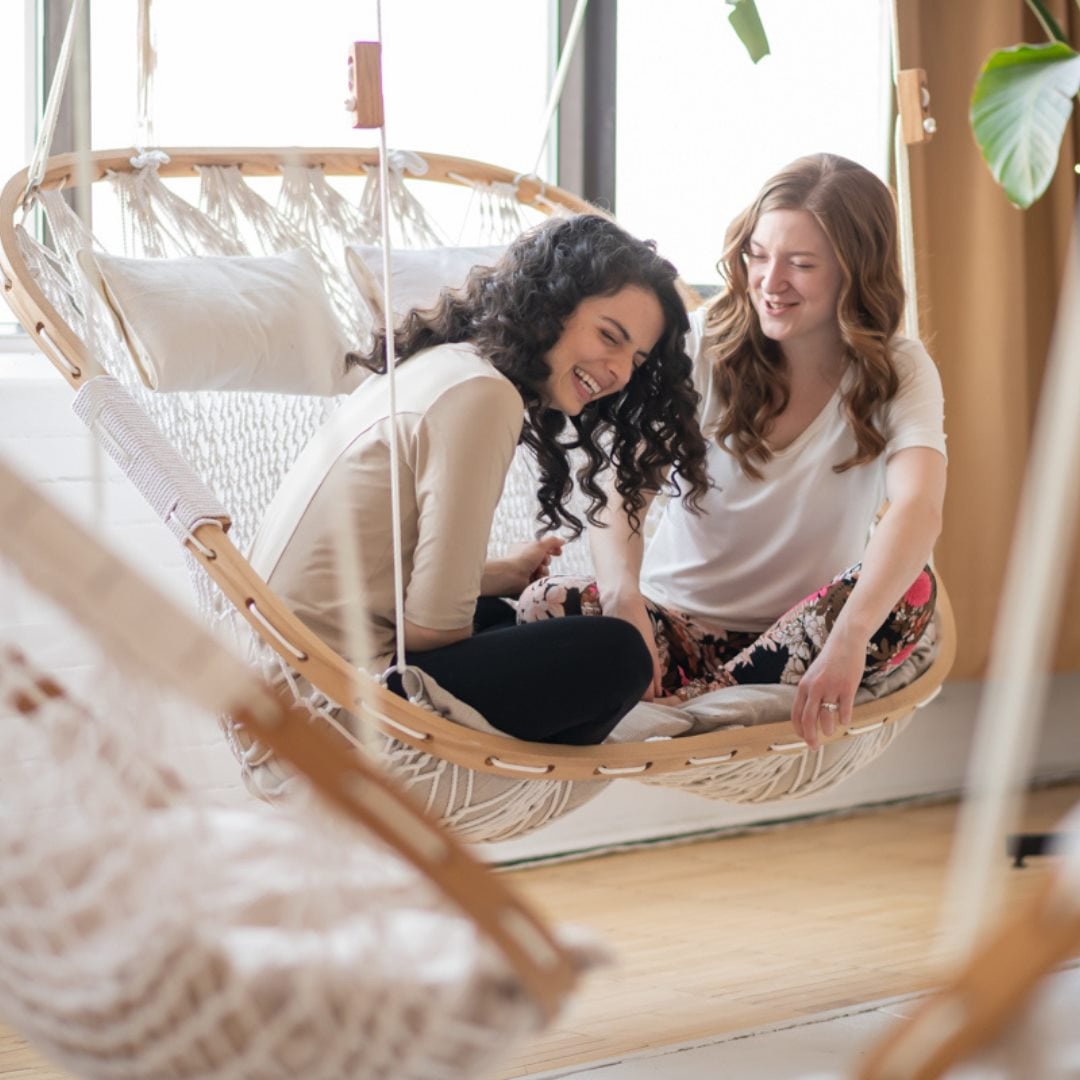 Hammock Chairs for Relationship Building - two young ladies sitting in a Cobble Mountain Double Hammock Laughing together.