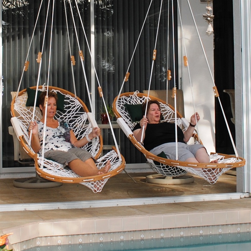Two ladies lounging next to each other in their own Cobble Mountain Summit chair with Foothold in front of a pool.