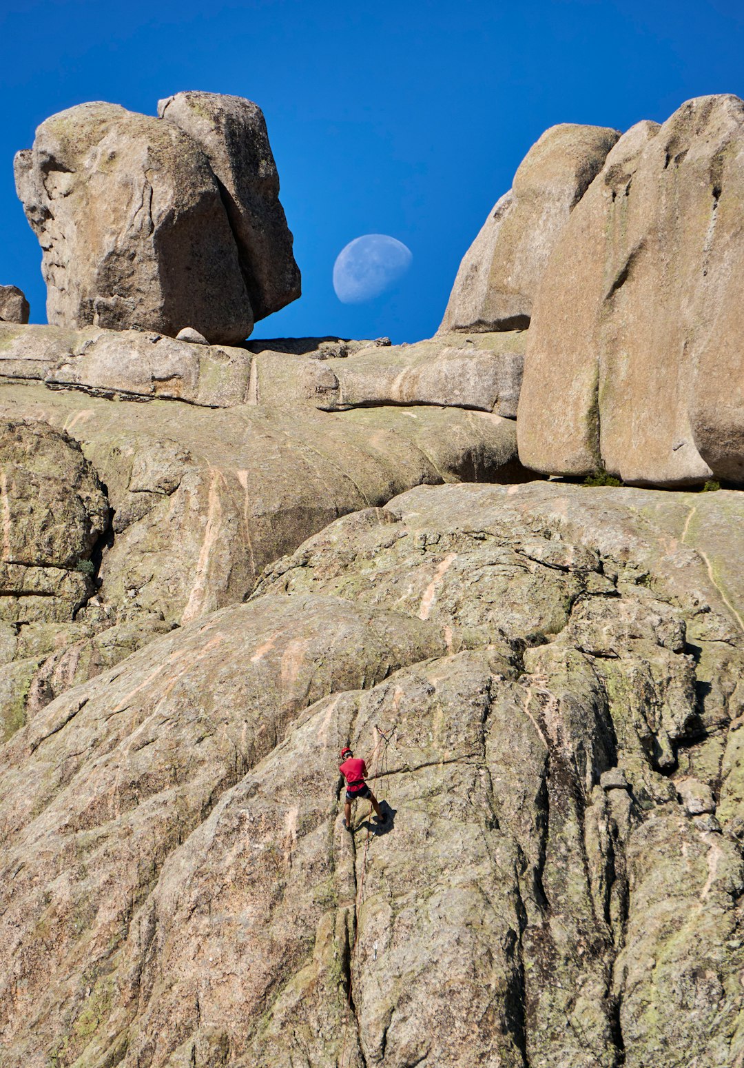 a Rout in La pedriza rocks with a climber in red rapelling with a rope. For the page Rock Climbing in Spain
