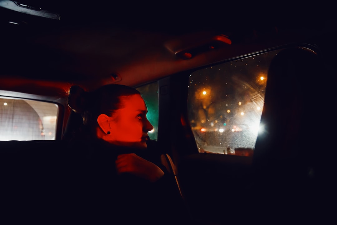 pic of a woman in a car at night looking sideways out of the window.