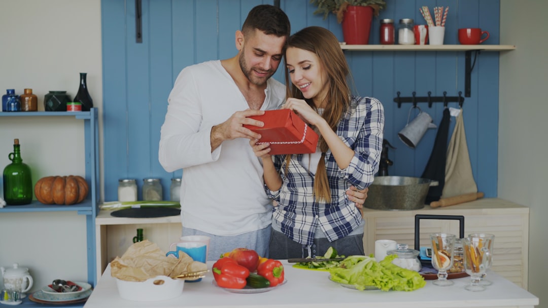Young married couple in the kitchen both looking at a wrapped gift together