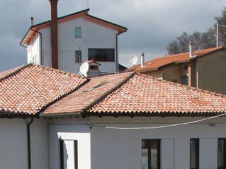 Außenansicht des Ostello La Finestra mit grauer Fassade und rotem Ziegeldach in den Julischen Alpen.