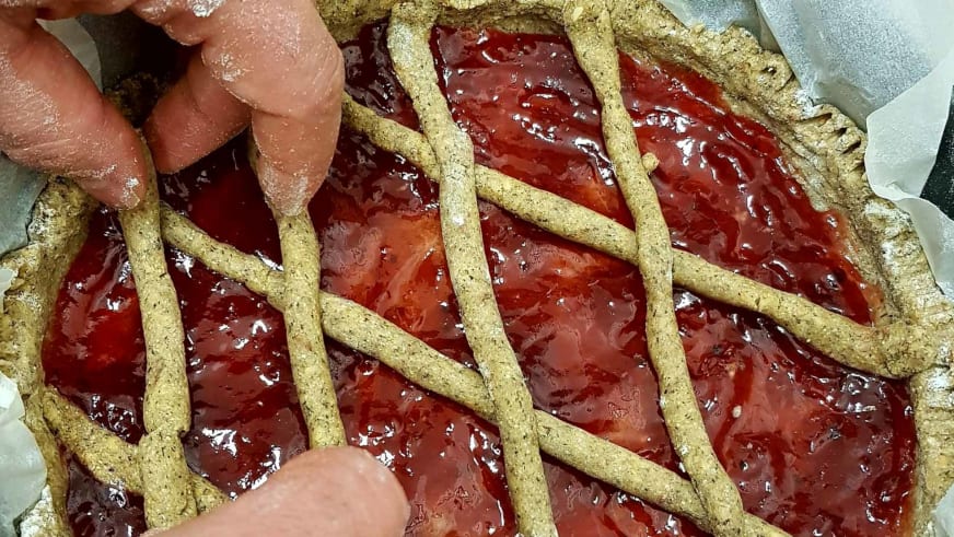 Hausgemachte Obsttarte mit Erdbeeren entsteht in der Küche des Hotel Aurora Duino mit Gitterteig und Fruchtfüllung.