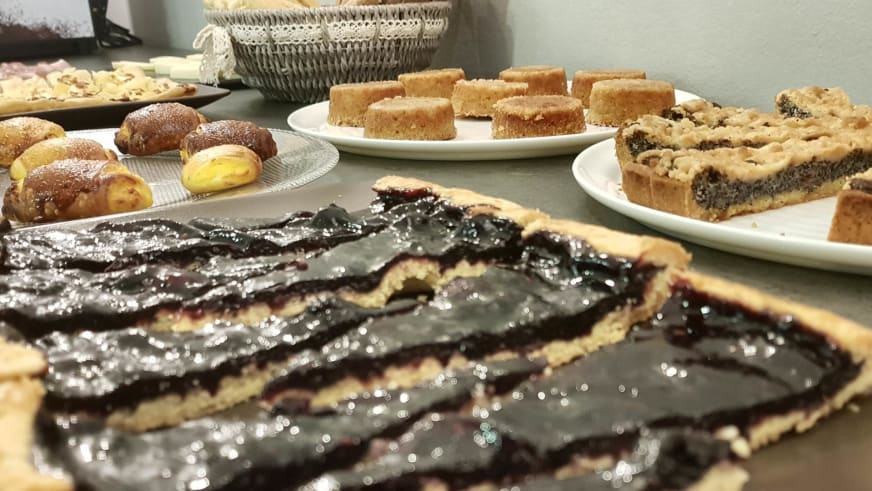 Dessertbuffet im Hotel Aurora Duino zeigt Schokoladenkuchen, Windbeutel und Mohnkuchen auf weißen Tellern arrangiert.