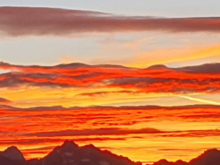 Bergpanorama bei Dämmerung von der Siegerlandhütte mit orange-gelbem Himmel über den Stubaier Alpen.