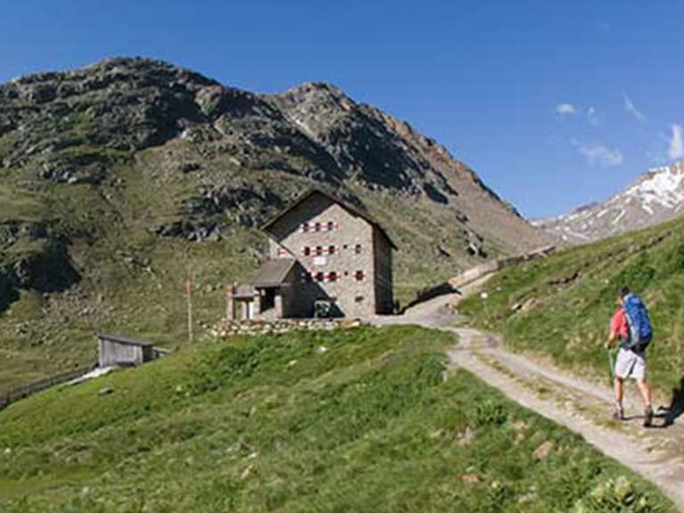 Bergwanderer auf dem Zustieg zur Martin-Busch-Hütte in den Ötztaler Alpen mit schneebedeckten Gipfeln im Hintergrund.