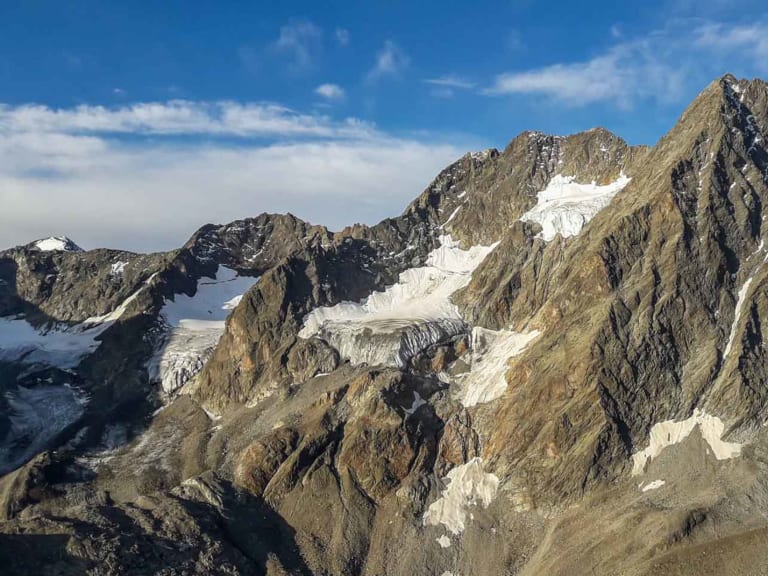 Bergwanderung am Kaunergrat: spitzer Felsengipfel mit fragmentiertem Gletscher, Seracs und Schutzhütte auf felsigem Hang im Pitztal.