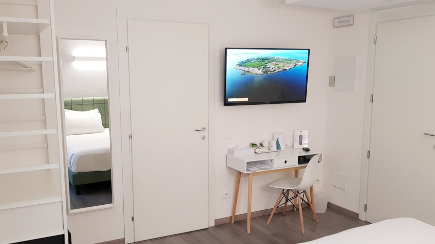 Familienzimmer im Hotel Aurora Duino zeigt weißes Stockbett, Schreibtisch und separaten Schlafbereich mit grünem Kopfteil.