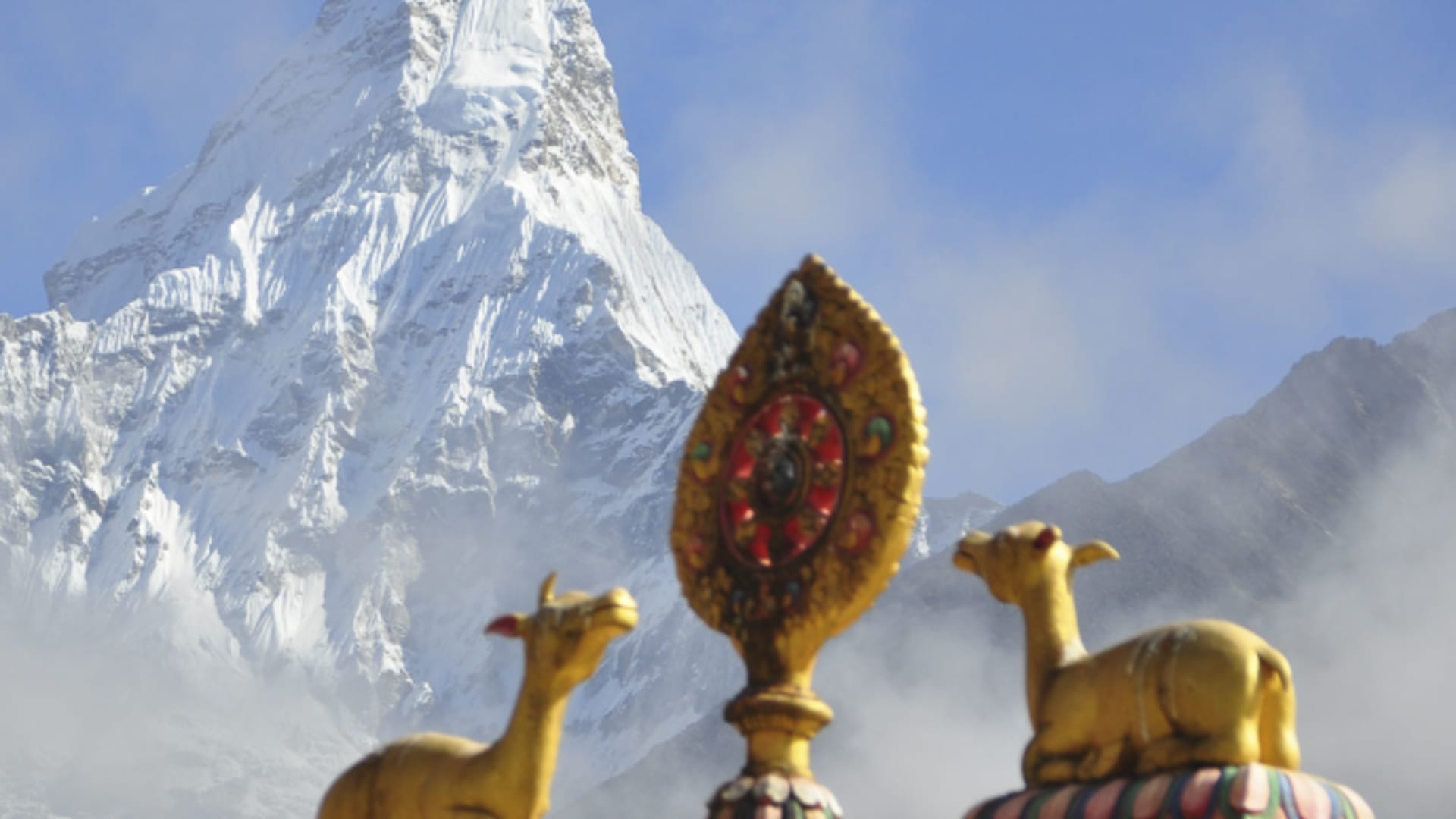 Vergoldete Tempelornamente auf Klosterdach mit pyramidenförmigem Hochgebirgsgipfel im Hintergrund im Sagarmatha-Nationalpark.