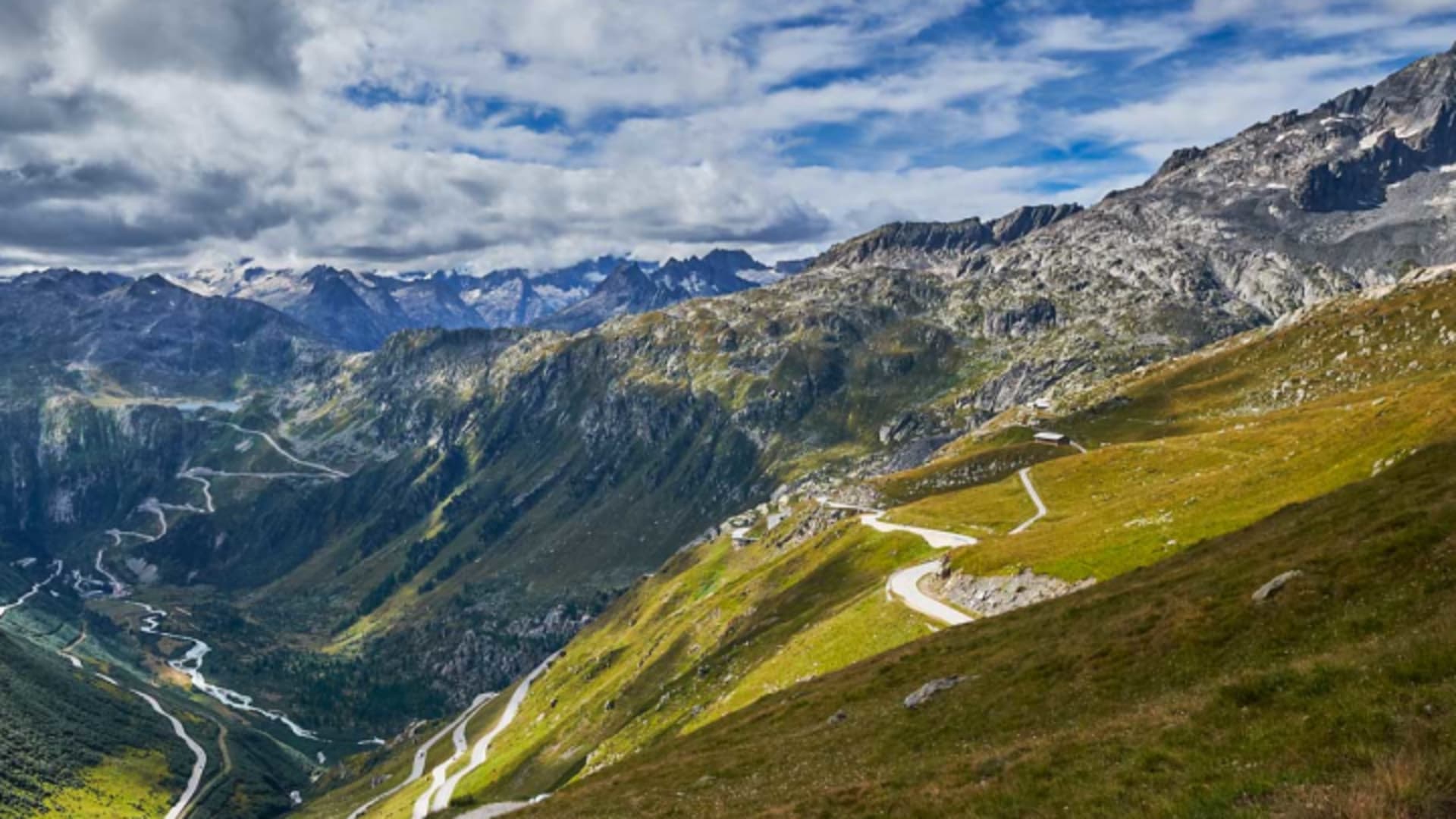 Bergwanderung über einem Walliser Alpental mit Passstraße, mäandrierendem Fluss und vergletscherten Gipfeln.