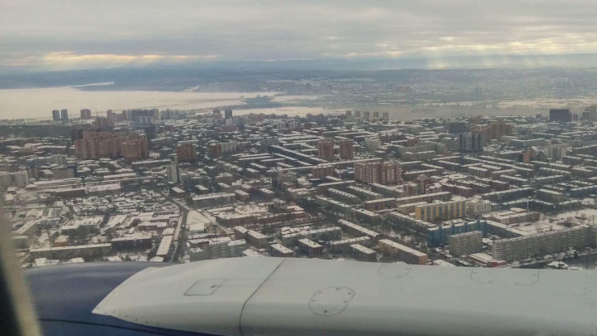 Blick aus dem Flugzeugfenster auf die schneebedeckte Großstadt Irkutsk als Ausgangspunkt für Skitouren am Baikalsee.