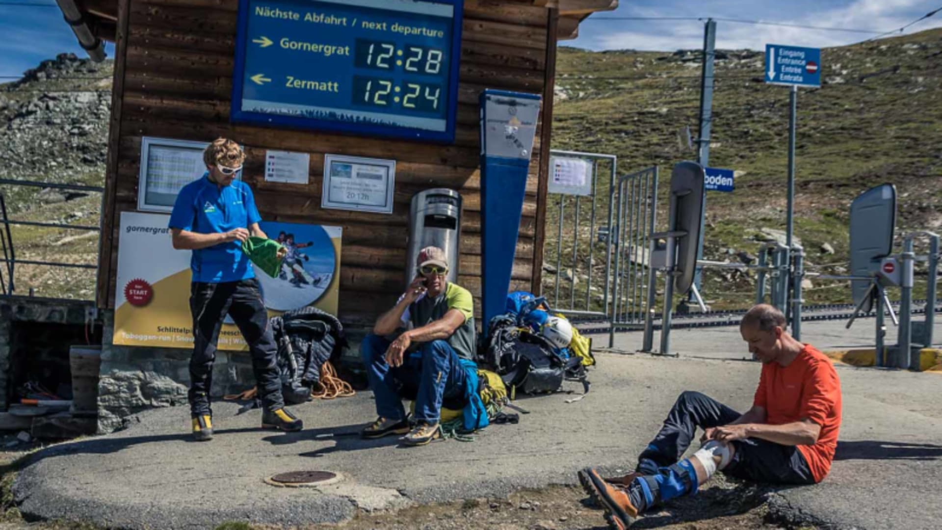 Bergwanderer an der Bahnstation Rotenboden mit Abfahrtsanzeige Richtung Zermatt im Sommer.