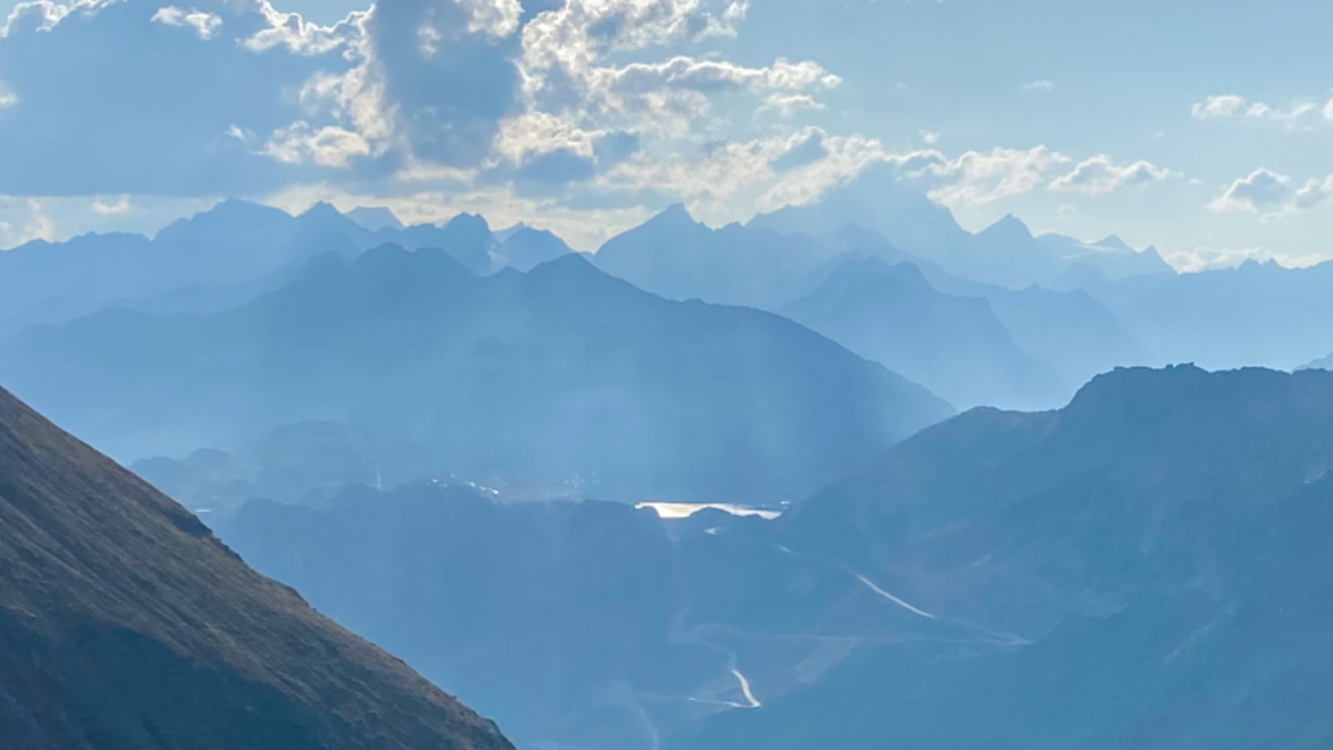 Bergwanderung am Furkapass mit Panorama auf das Finsteraarhorn und gestaffelte Gebirgsketten im bläulichen Dunst.