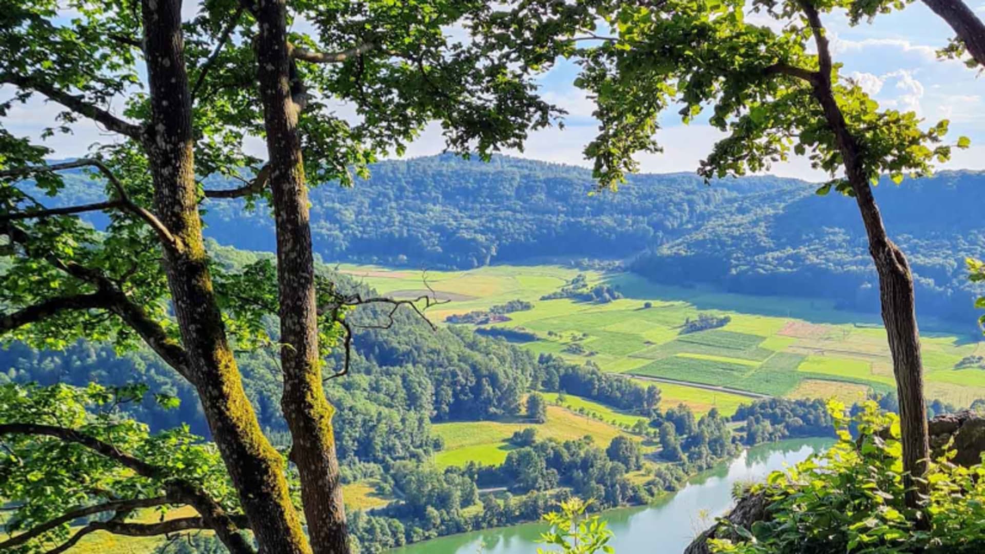 Bergwanderung Hersbrucker Schweiz: Weitblick von Felskanzel durch Laubbäume auf Fluss und Tallandschaft.