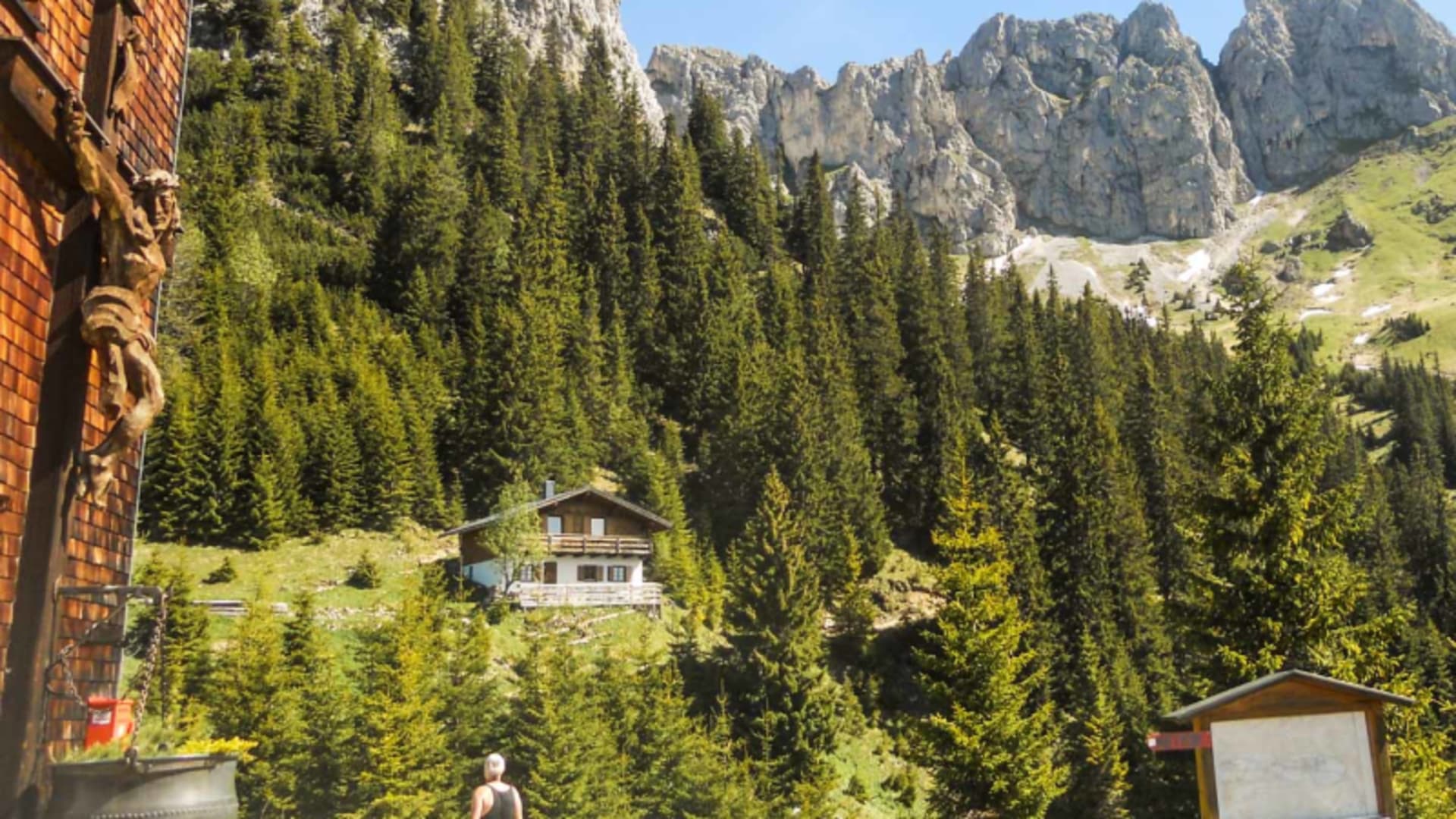 Bergwanderer steht vor dem Gimpelhaus im Tannheimer Tal mit Almhütte und felsigen Graten im Hintergrund.