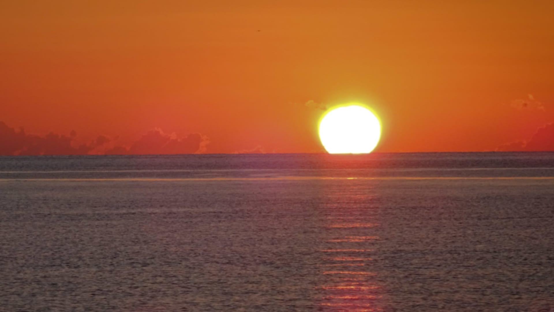 Bergwanderung an der Küste Sardiniens – Sonnenuntergang über flacher Meeresoberfläche mit rotem Horizont.