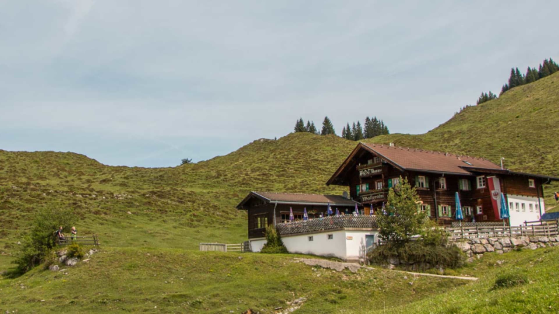 Blick auf die Walleralm mit Außenterrasse und Sonnenschirmen bei der Bergwanderung zur Kaiserkrone in Tirol.
