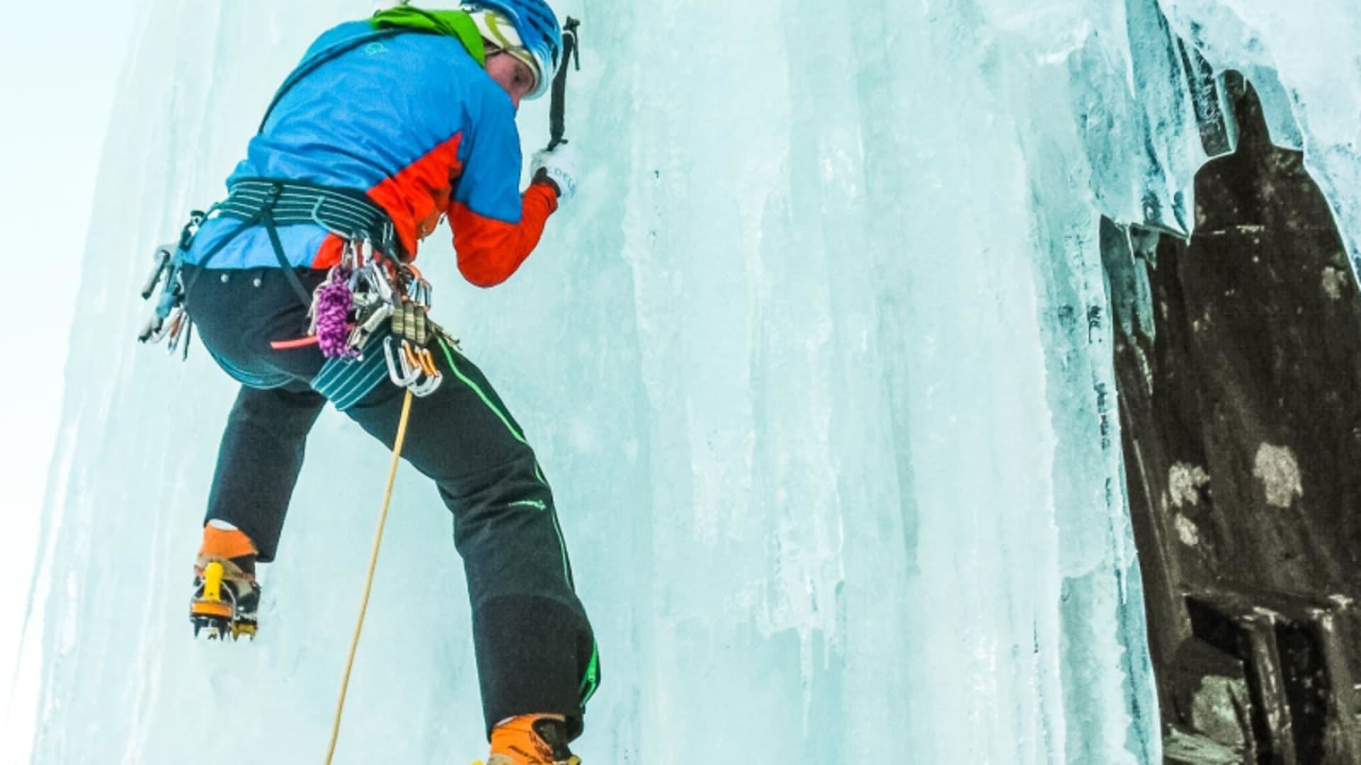 Eiskletterer mit Steigeisen und Eispickeln klettert in Froschperspektive an senkrechter Eiswand in Rjukan.