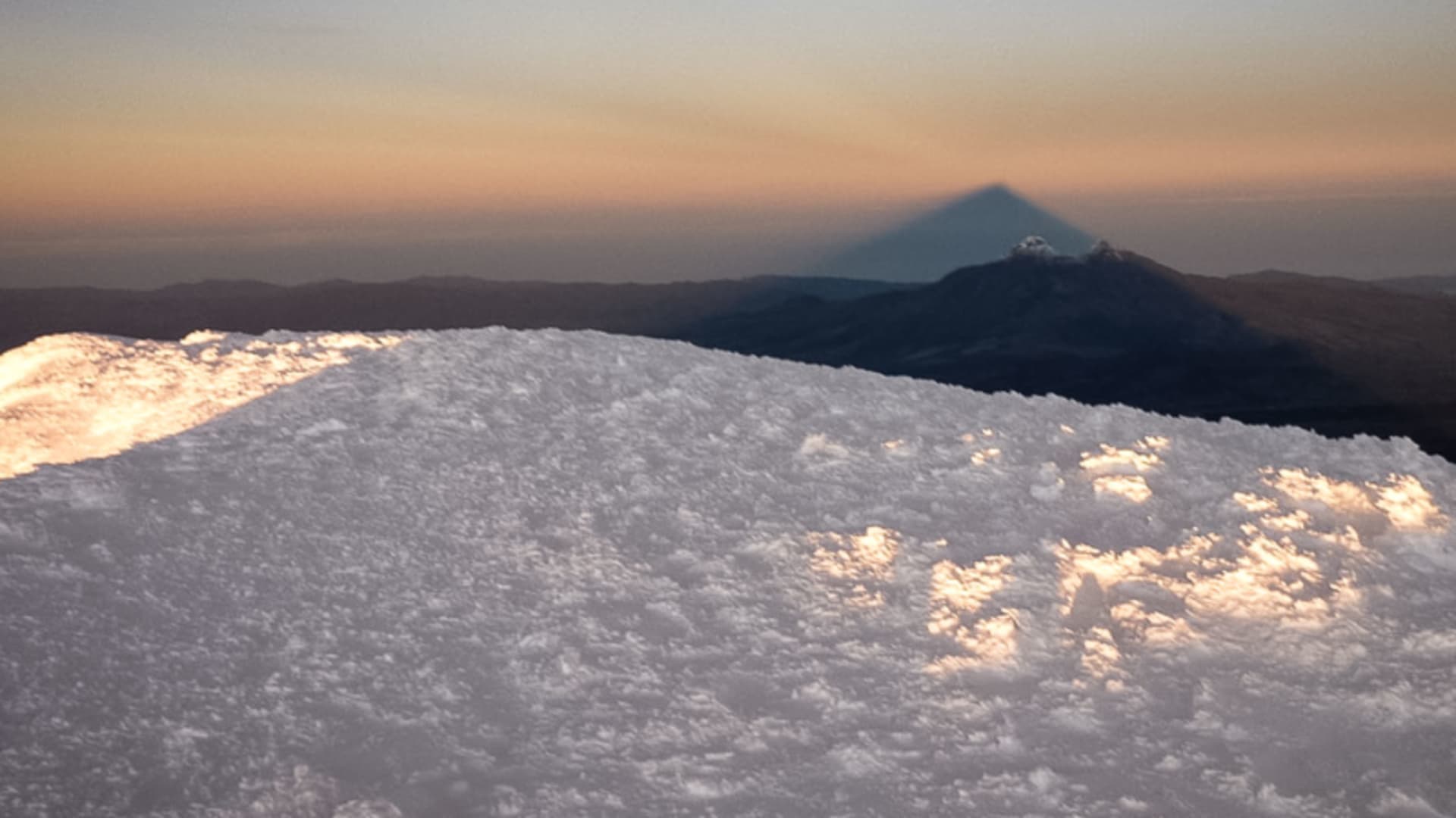 Expedition Chimborazo: Blick vom Gipfelgletscher auf den Cotopaxi im Morgen- oder Abendlicht.