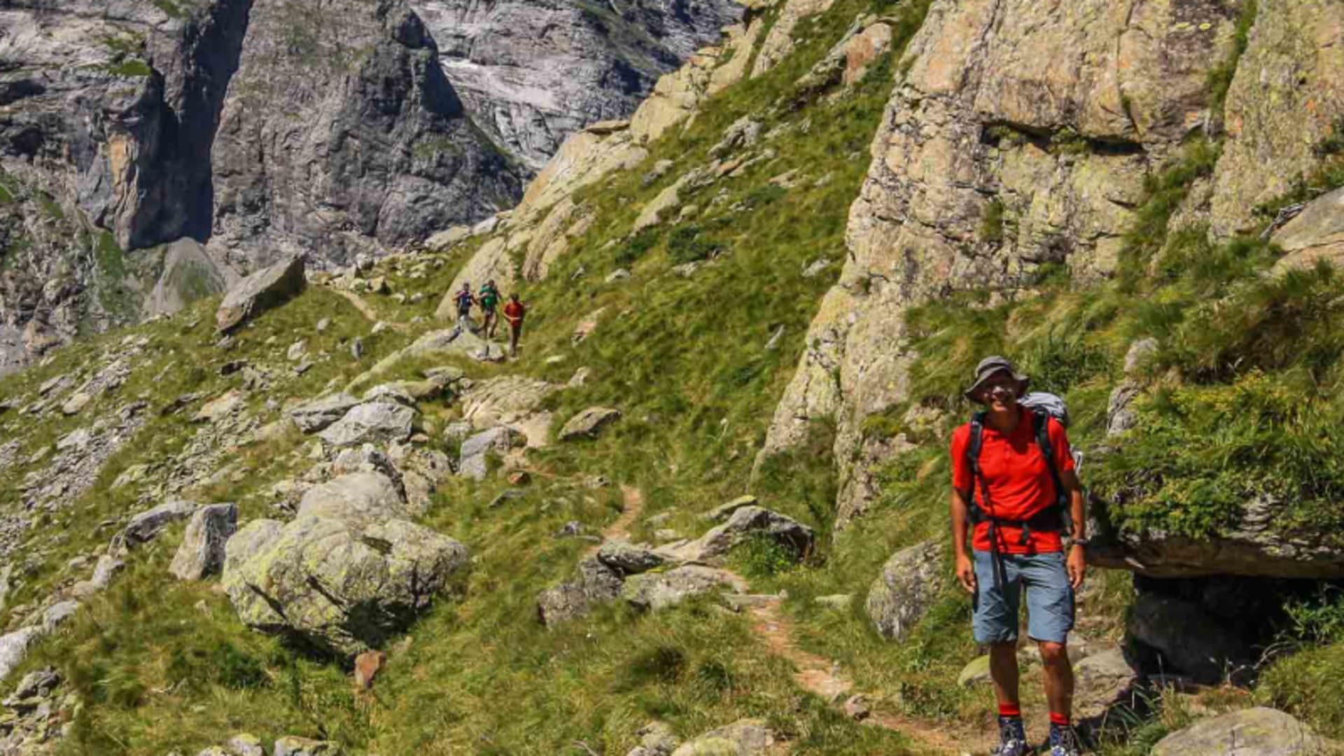 Drei Bergsteiger auf schmalem Wanderpfad an grasbewachsenem Hang beim Aletschgletscher, Hochtour mit Bergführer