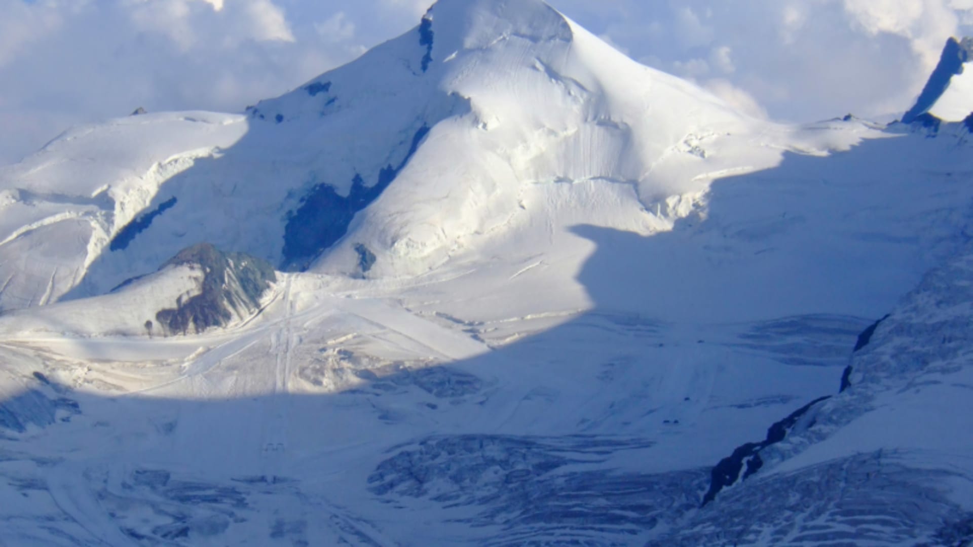 Hochtour auf das Allalinhorn: Panoramaansicht des schnee- und eisbedeckten Gipfels mit Schneegrat und Gletscherplateau