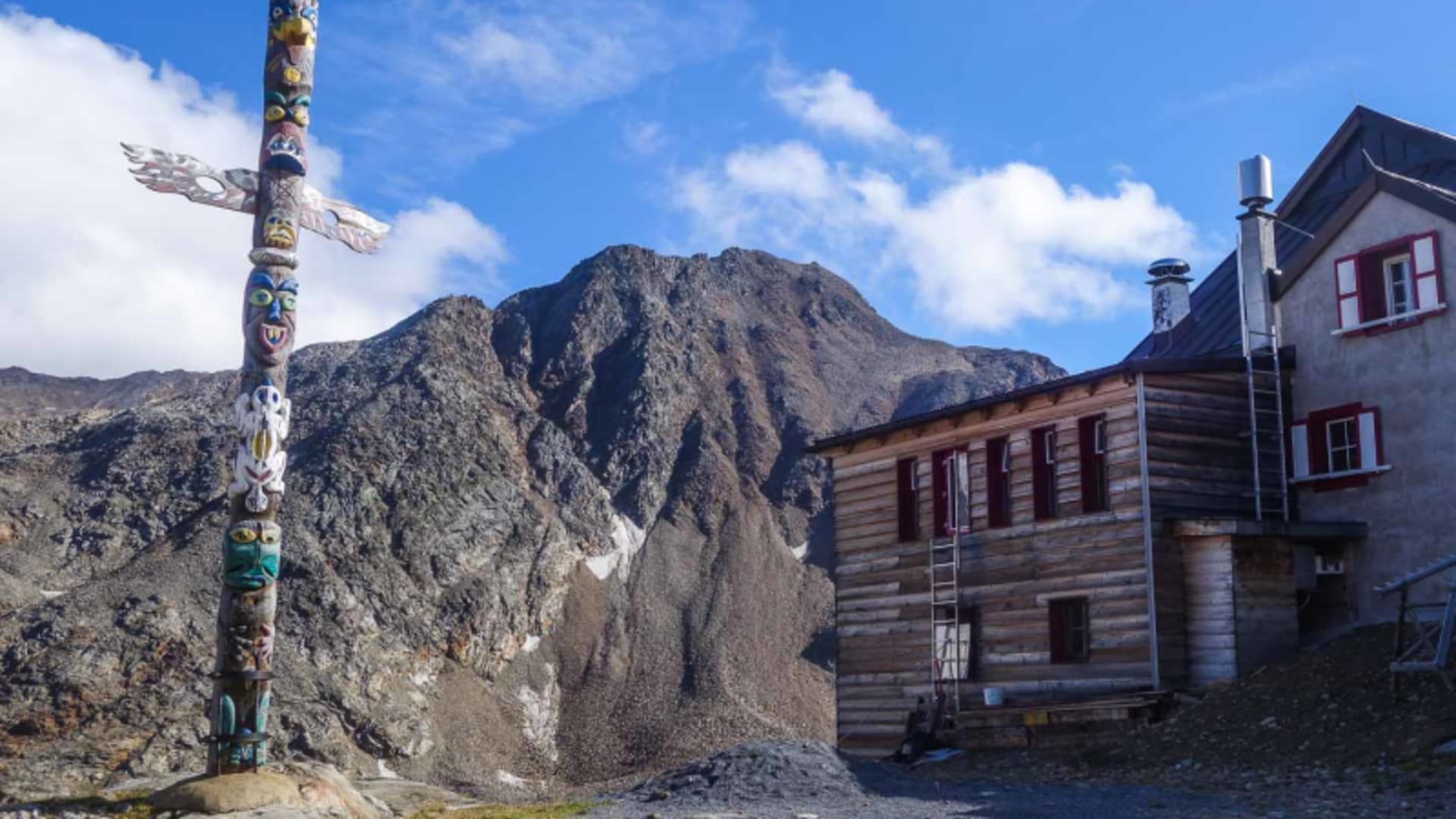 Hochtour im Ötztal: Blick auf die Bella Vista Hütte mit Holzgebäude, Neubau und Totempfahl im Vordergrund.