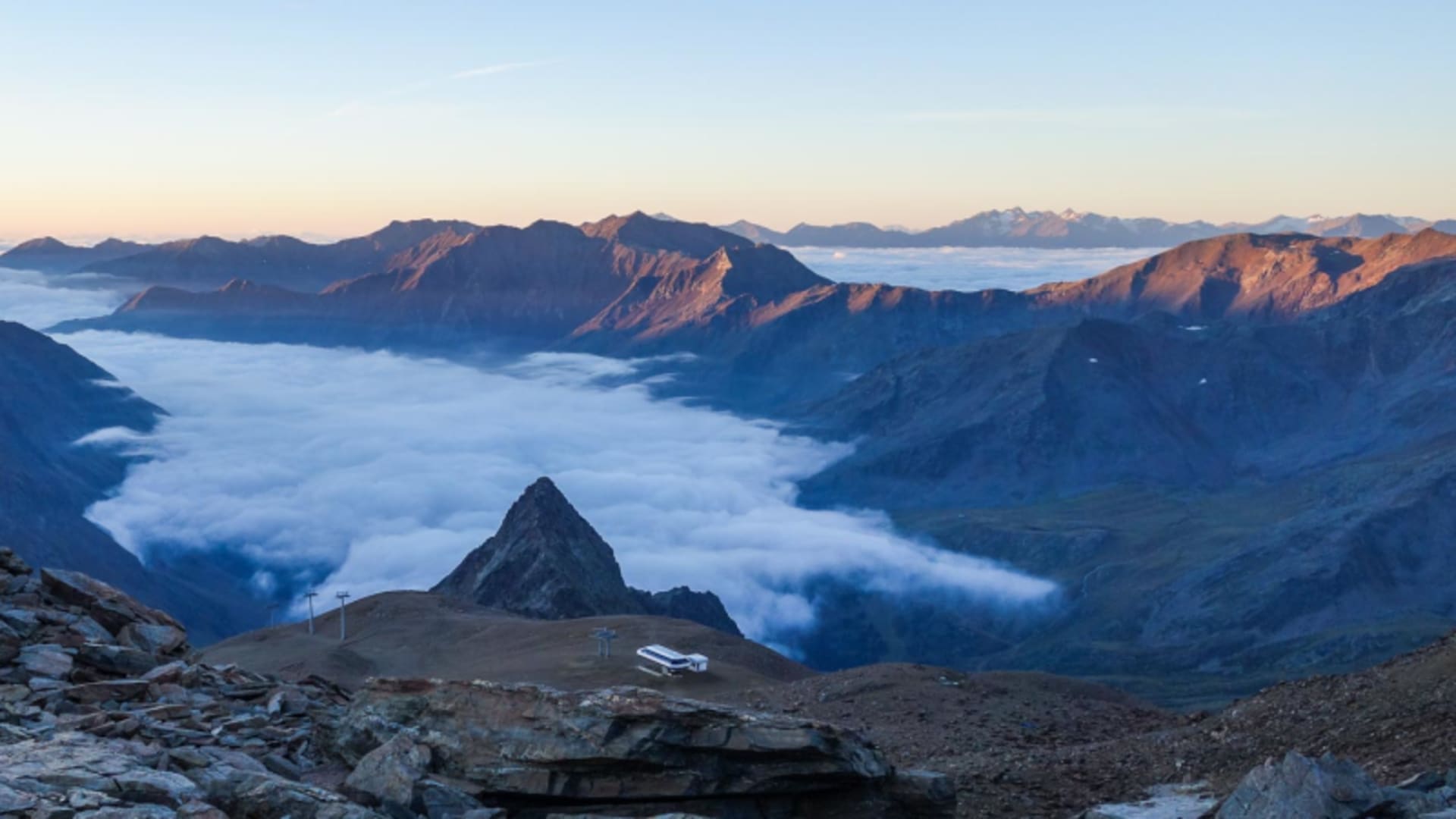 Hochtour auf der Ötztaler Runde: Felsturm ragt aus Wolkenmeer, Bergketten im Morgenlicht.