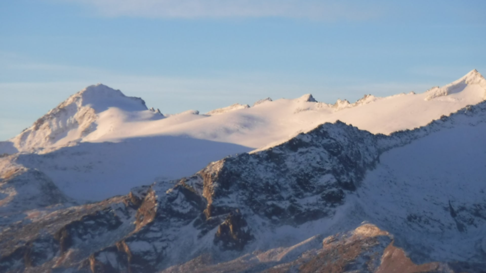 Hochtour an der Presanella: verschneiter Gebirgskamm mit felsigen Gratspitzen im warm-rötlichen Seitenlicht.