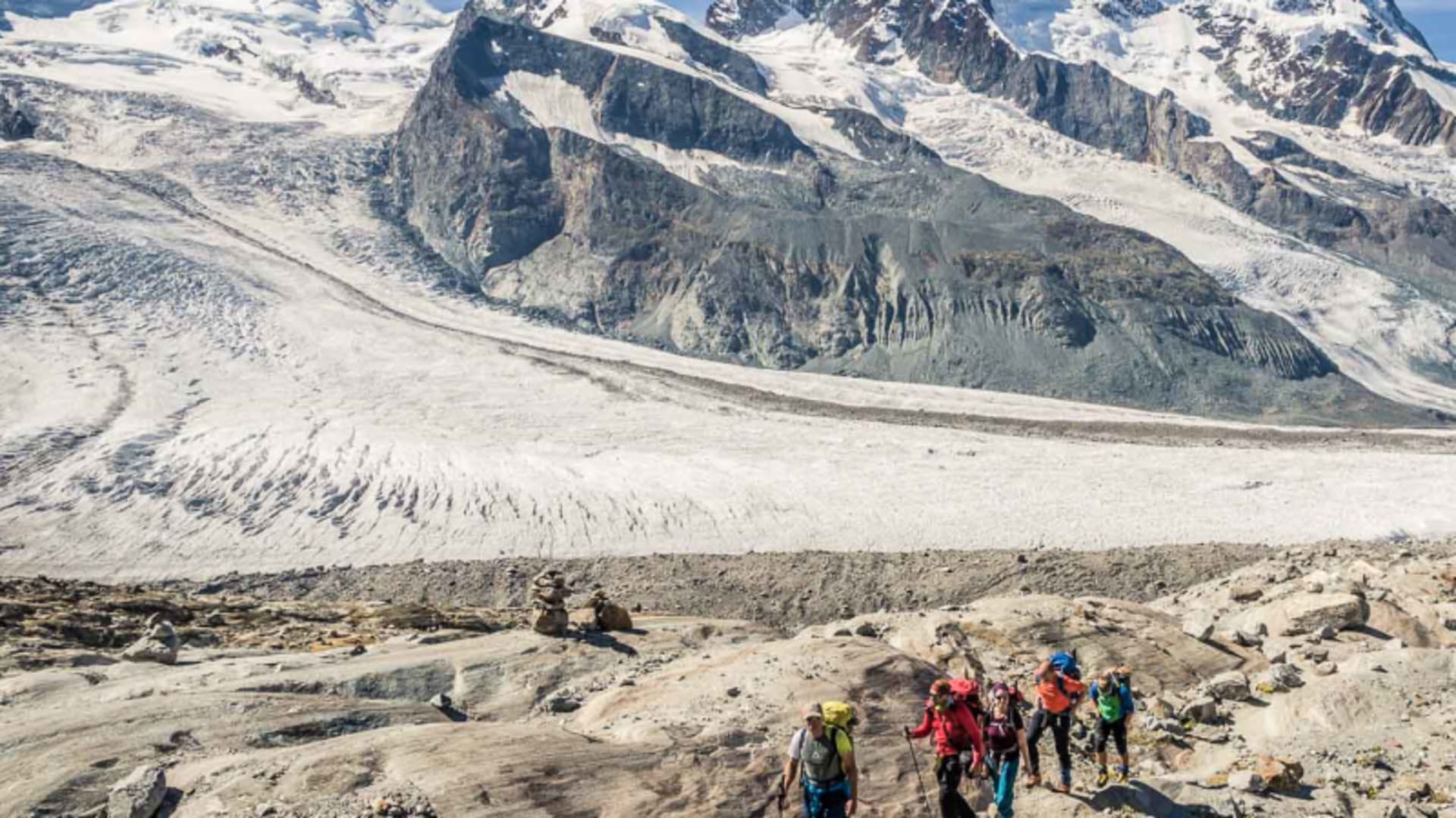 Hochtour in Zermatt: Bergsteigergruppe steigt über felsige Moräne am Grenzgletscher mit Hochgebirgspanorama auf.