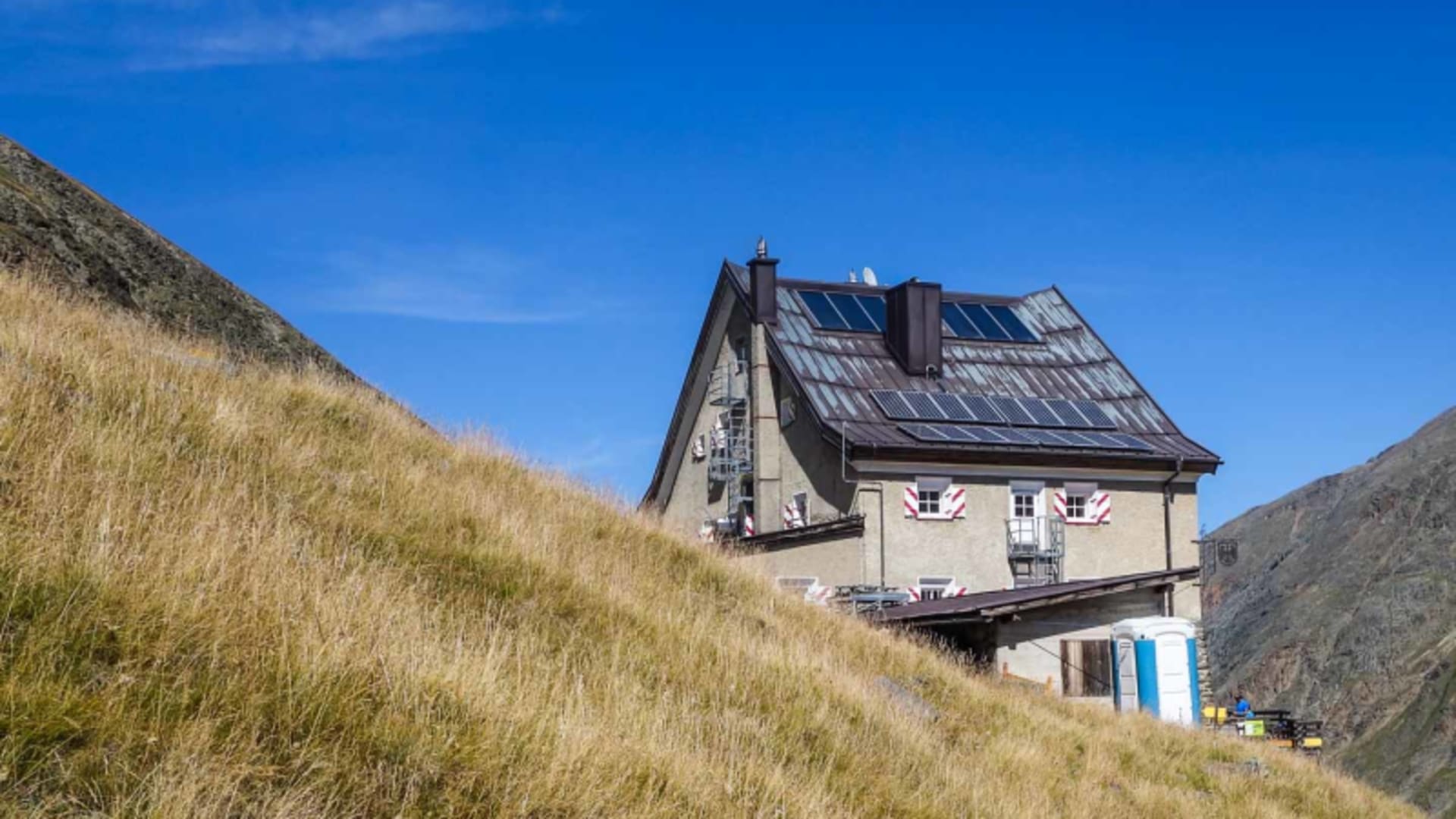 Hochtour im Ötztal: Das Hochjoch Hospiz mit Solarpaneelen auf dem Dach, eingebettet in felsige Berghänge.