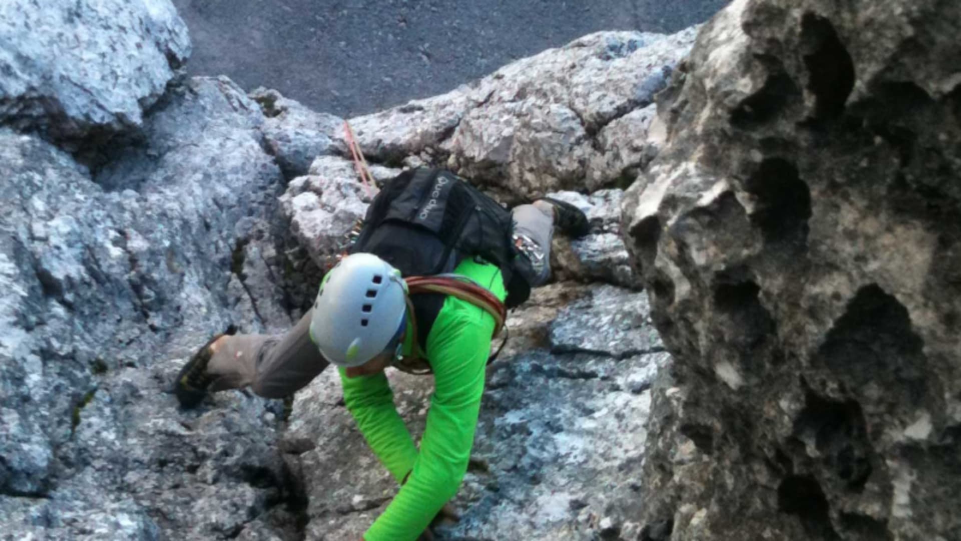 Klettern am Waxenstein: Vogelperspektive auf Kletterer mit grünem Shirt, Helm und Rucksack an Kalksteinfels.