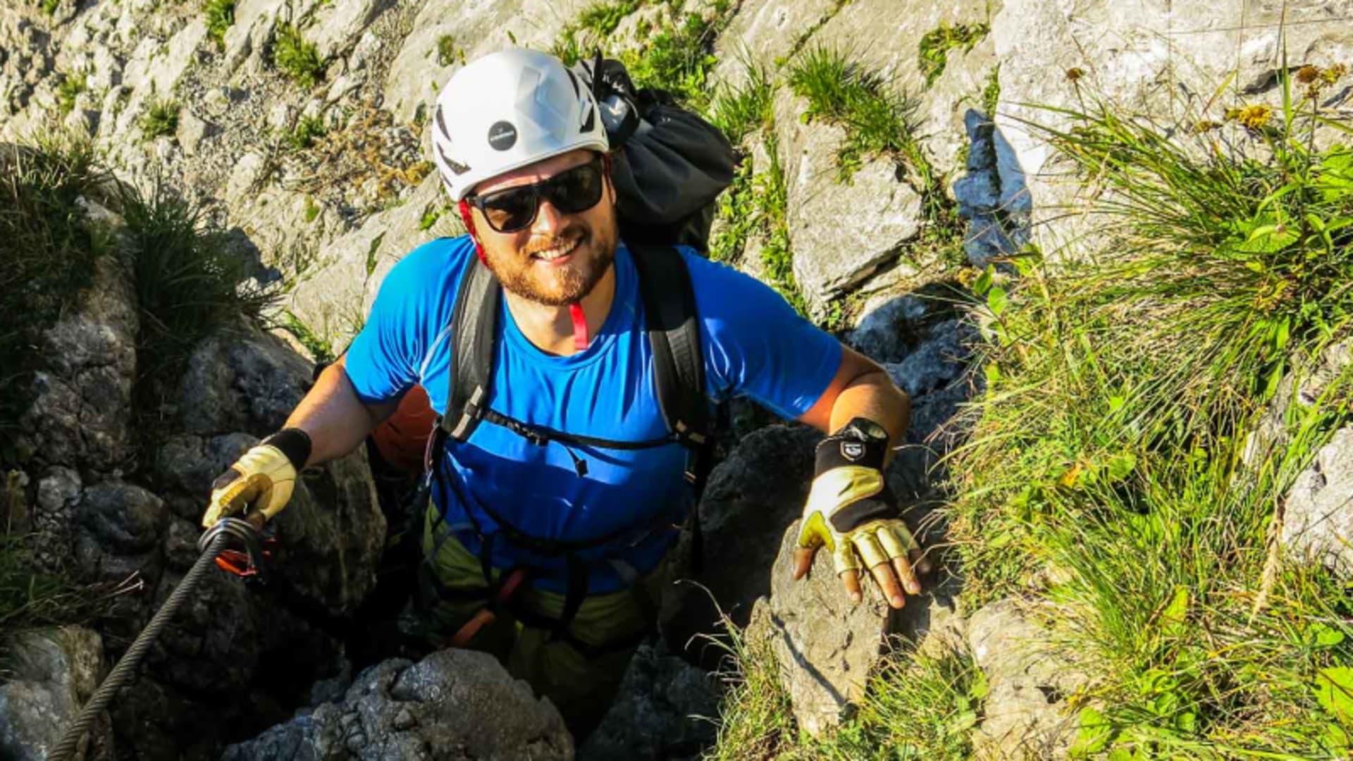 Klettersteiggeher greift am Einstieg zur Zugspitze ins Stahlseil und steigt den Kalkfels aufwärts.